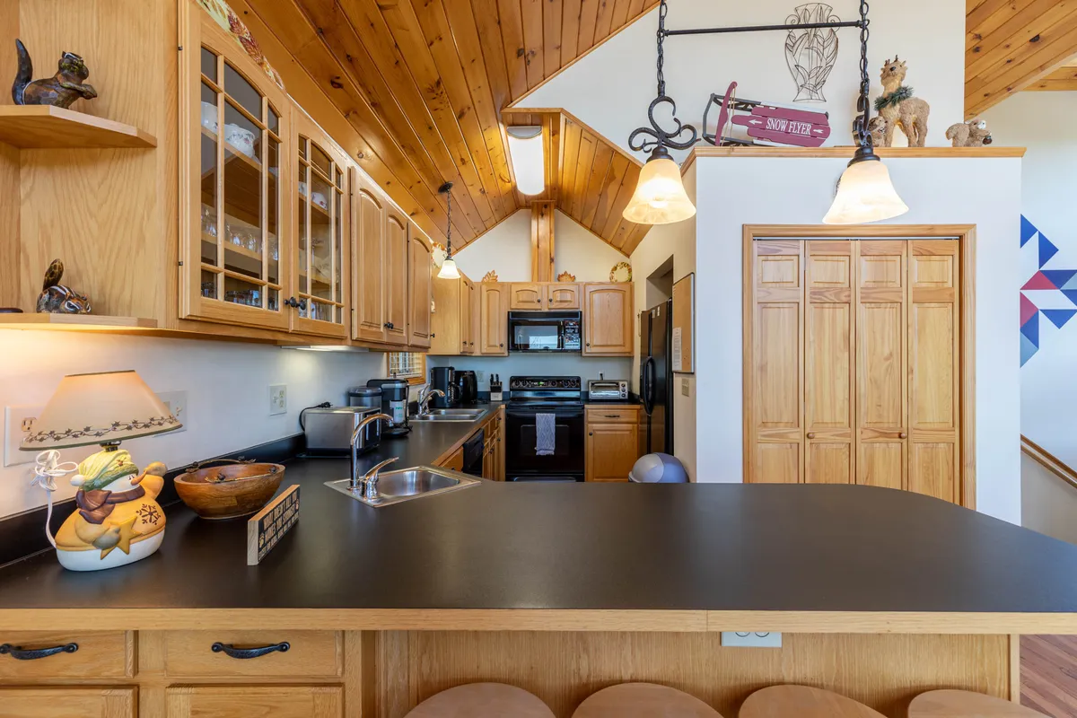 A spacious kitchen with a central island, wooden cabinetry, and stylish lighting fixtures. The open plan and inviting atmosphere make it ideal for gathering, prepping snacks for an adventure, or hosting casual get-togethers—including with pets at your feet.