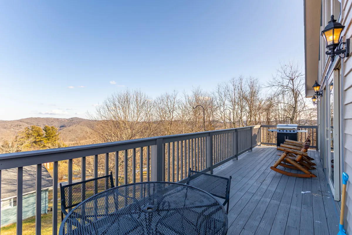This scene captures an exterior view with patio furniture and a grill overlooking breathtaking mountain vistas. It evokes the peaceful mood of early mornings or evenings spent outdoors, enjoying the view and fresh mountain air.